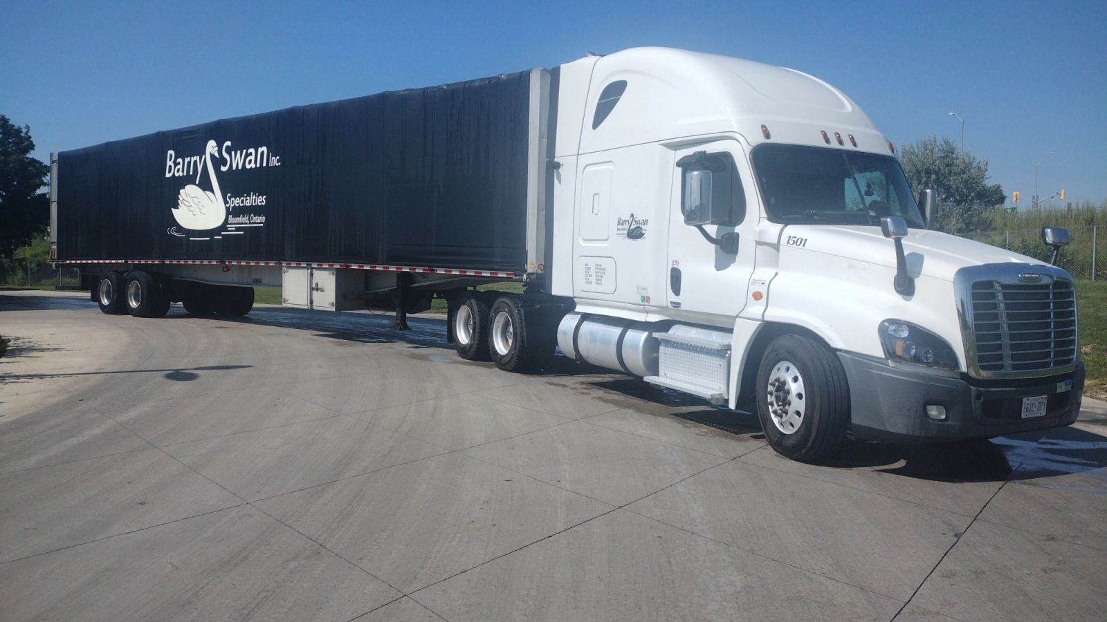 A white Barry Swan tractor with a black company-branded trailer at the Bloomfield yard