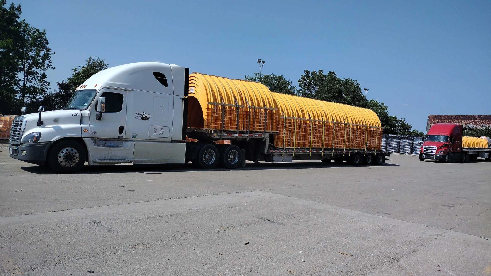 A Barry Swan tractor hauling large yellow industrial components on an open trailer